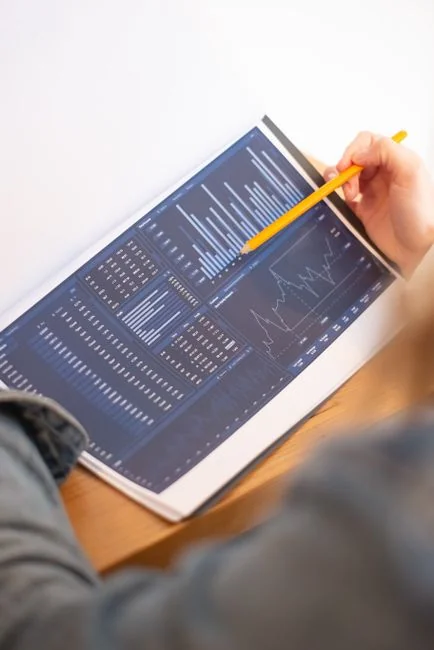 Close-up of hands pointing at a financial market activity chart, analyzing trends in securitization.